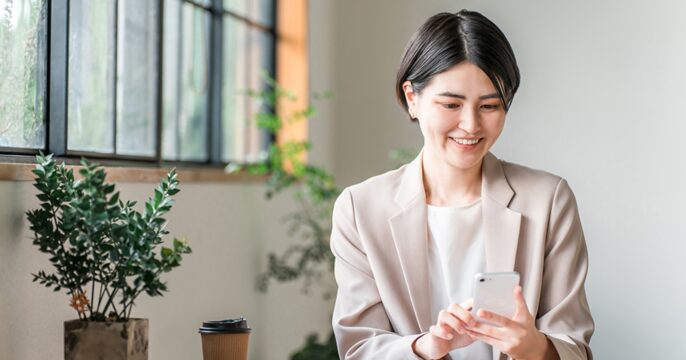 スマホを使って派遣会社に登録をしている女性のイメージ