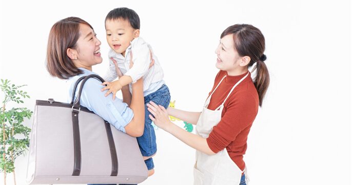 仕事終わりの母親が幼い子どもを保育園まで迎えに来たイメージ