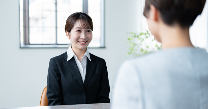 派遣の職場見学で、派遣先職員からの質問に対しハキハキと回答している女性の画像