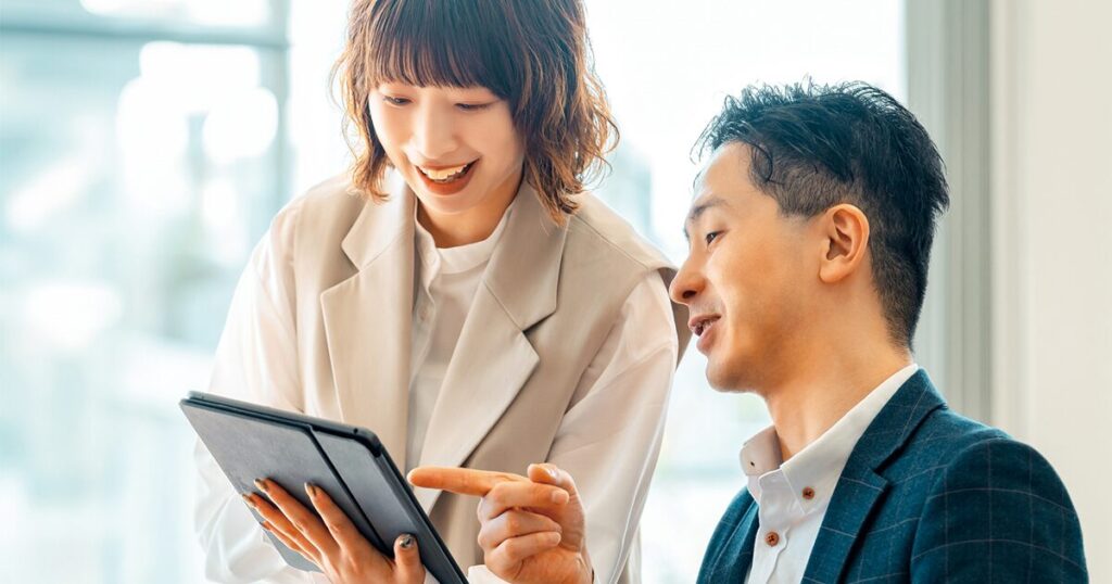 営業事務の女性が営業担当者と業務内容を確認しているイメージ