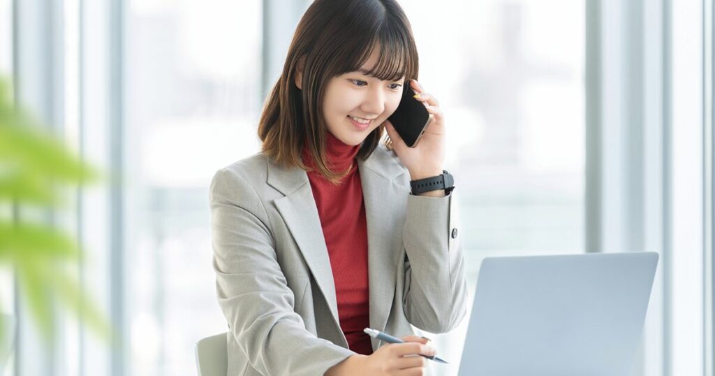 営業事務として電話対応と事務作業を同時に行う女性のイメージ