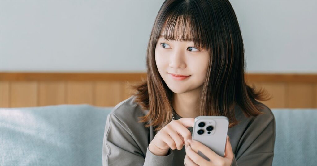 派遣の仕組みや正社員との違いをスマホで調べる女性のイメージ