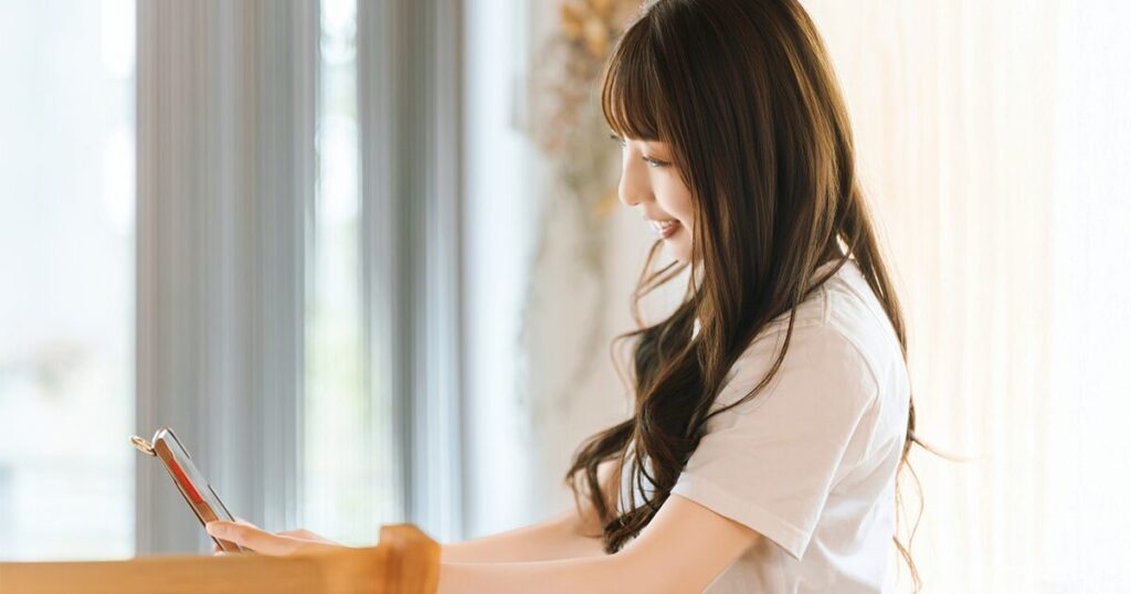 スマホを使って自分に合ったひとり事務の求人を探す女性のイメージ