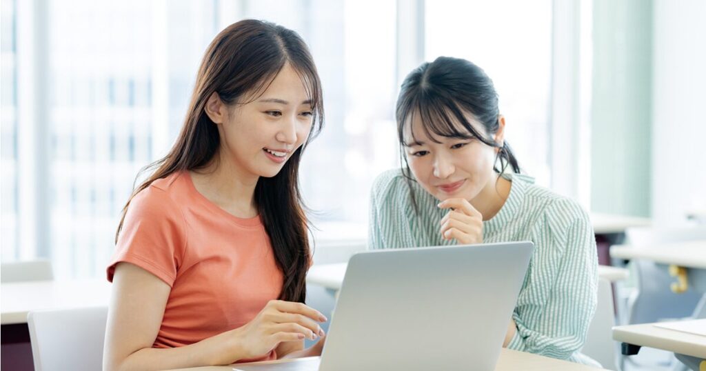 大学生が友人と一緒に、学生でも働ける派遣の求人を探しているイメージ