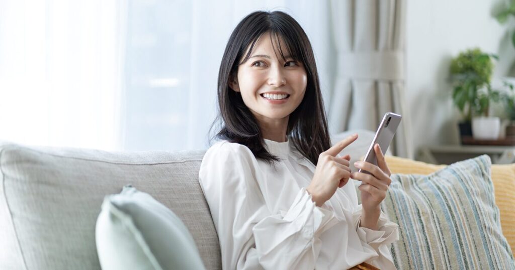 派遣契約満了後の次の仕事を探すために、スマホで求人情報を確認している女性のイメージ