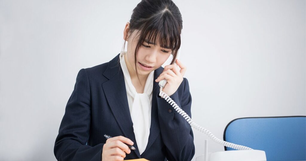 仕事で受けた電話で「致しかねます」を使った断り方に悩んでいる女性のイメージ
