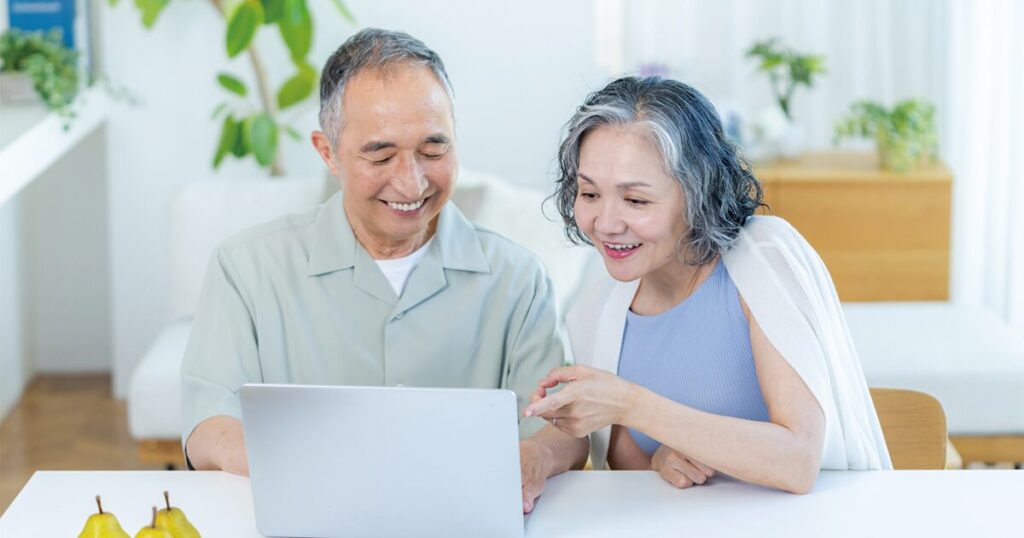 定年後の再就職や給与事情について、パソコンを見ながら相談する60代の夫婦