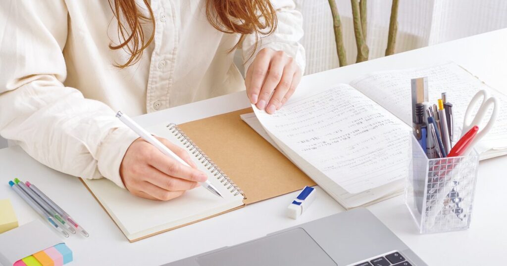 総務の仕事に役立つ資格取得に向けてノートを取りながら勉強している女性のイメージ