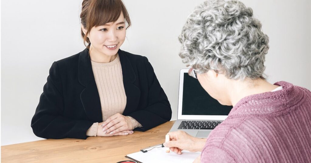 定年後の再就職や失業保険について、ハローワークの窓口で相談している60代女性