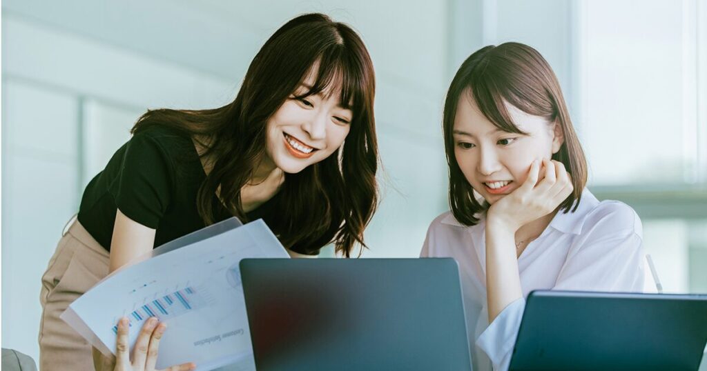 総務の仕事で同僚とコミュニケーションをとり、やりがいを感じながら働いている女性のイメージ