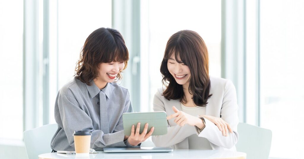 派遣の抵触日を迎えて無期雇用派遣へと転換し、同僚と楽しそうに働いている女性のイメージ