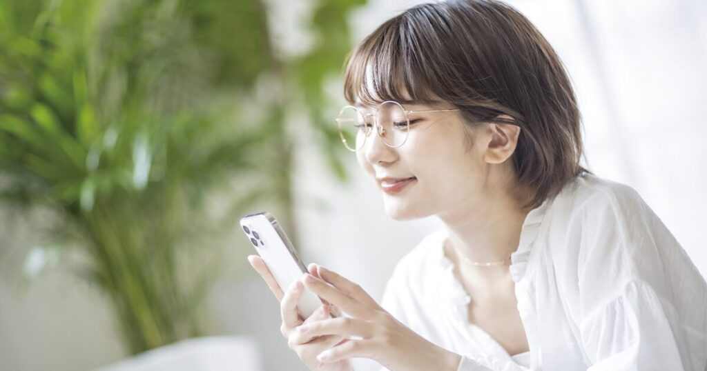 職場の人間関係に疲れ、転職を検討し、スマホで求人検索をしている女性