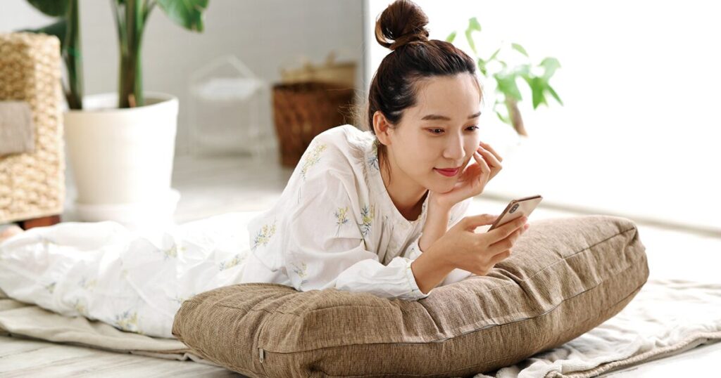 今の仕事のやる気がでず、スマホで派遣の仕事を探している女性
