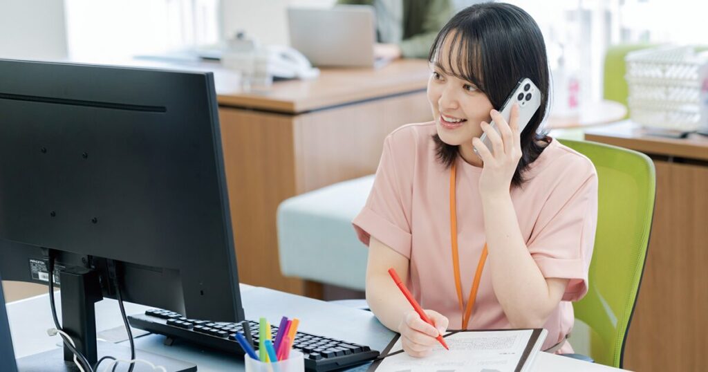 仕事の電話にビジネス敬語を使って対応している女性